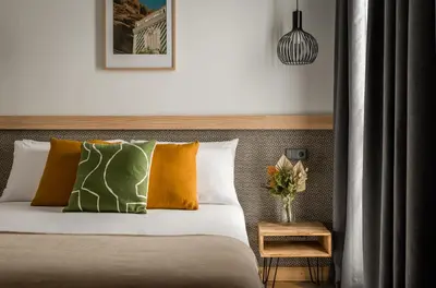 a bed with orange and green pillows in a bedroom at BYPILLOW La Sal in Cádiz