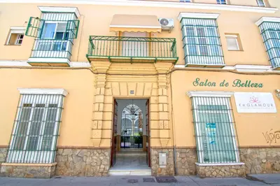 a yellow building with windows and a door at El Patio del Sol, Apartamentos Living Sur in Sanlúcar de Barrameda