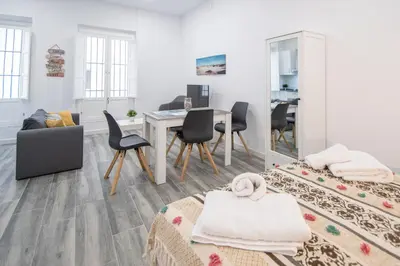 a white living room with a table and chairs at Estudio Al Sur de Cádiz in Cádiz