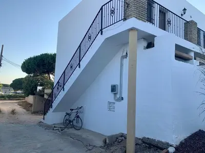 a bike parked next to a white building with a staircase at Conil, Colorado 2 rustico y económico in Conil de la Frontera