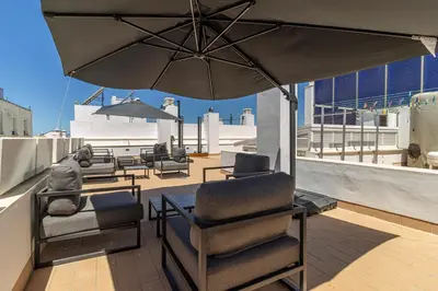 a patio with chairs and an umbrella on a roof at Allo Apartments San Roque Bajo A in Cádiz