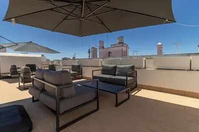 a patio with chairs and an umbrella on a roof at Allo Apartments San Roque 2ºA in Cádiz