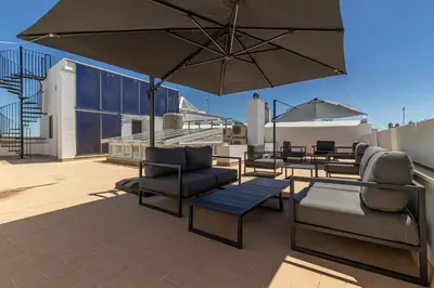 a patio with chairs and tables and an umbrella at Allo Apartments San Roque 3ºA in Cádiz