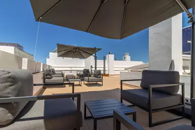 a patio with chairs and tables and an umbrella at Allo Apartments San Roque 3ºC in Cádiz