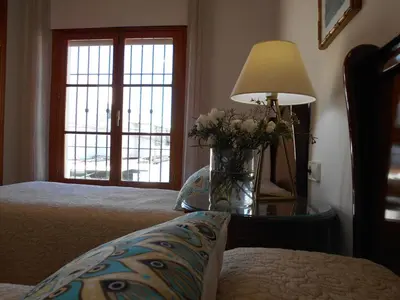 a bedroom with a vase of flowers on a table with a lamp at Penthouse Sleeps 4 with Private Garden in Chipiona