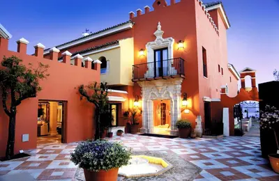 a large orange building with a courtyard with potted plants at Apartamentos Soho Boutique Vistahermosa in El Puerto de Santa María