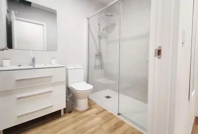 a bathroom with a toilet and a glass shower at APARTAMENTOS SANLUCAR CASA A in Sanlúcar de Barrameda