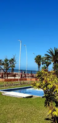 a swimming pool next to the ocean with palm trees at Playa Doñana 1 in Sanlúcar de Barrameda